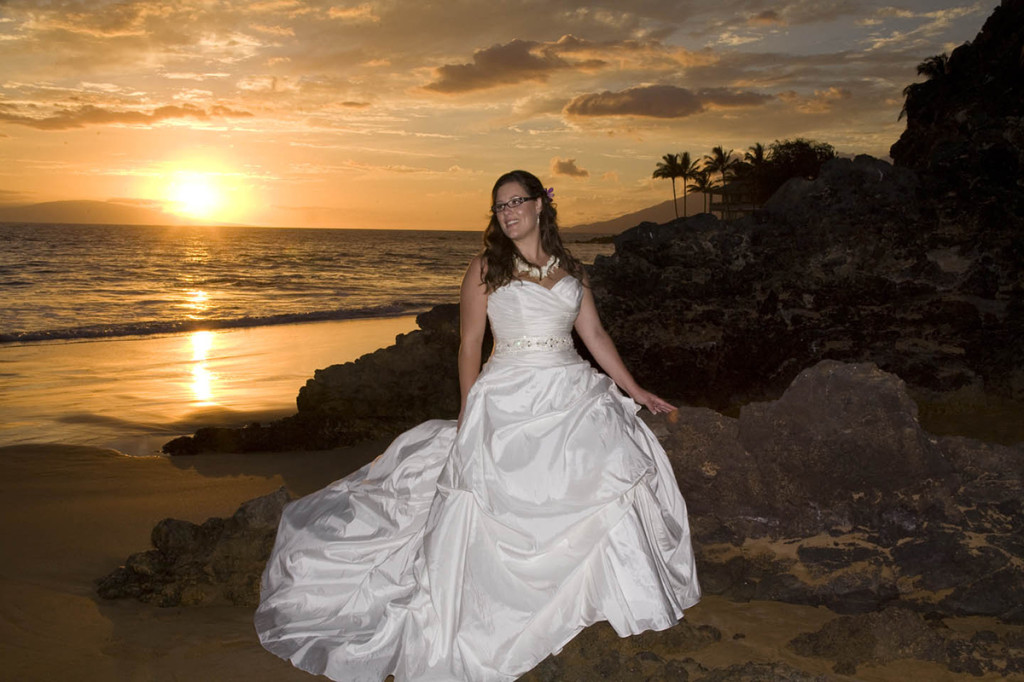 hawaii wedding bride sits on lava rocks on maui, posing for her wedding photography